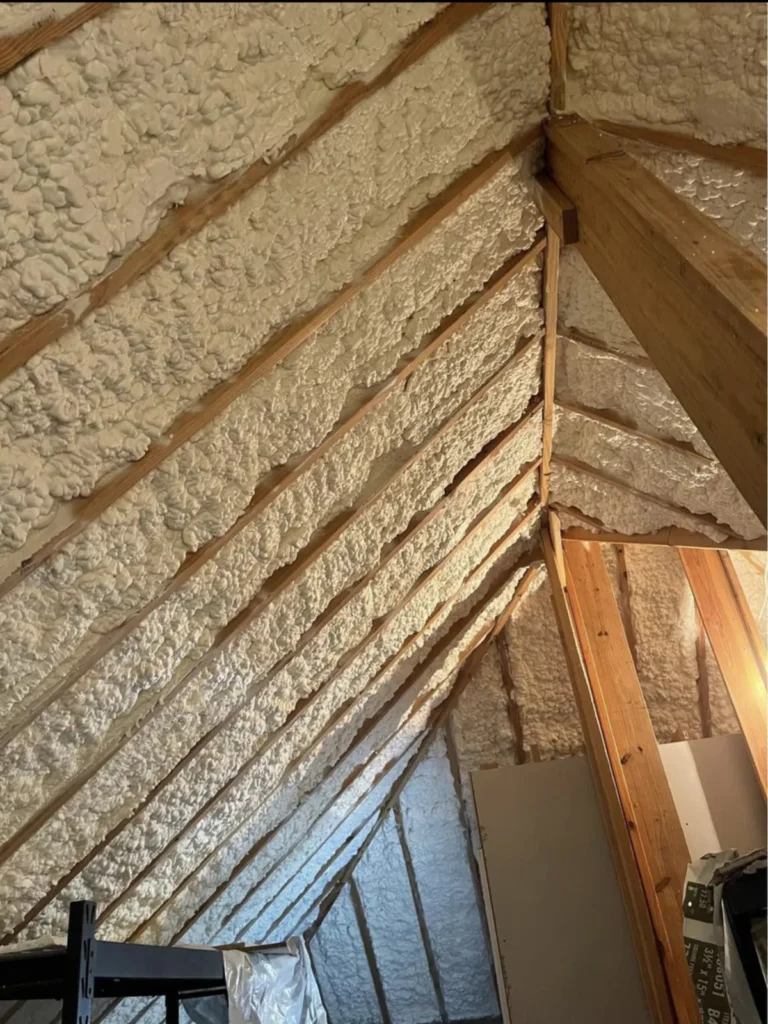 Spray foam insulation sprayed between wooden roof rafters in an attic